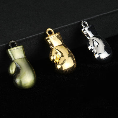 Three boxing glove charms in antique bronze-green, gold-tone and silver-tone finishes side by side