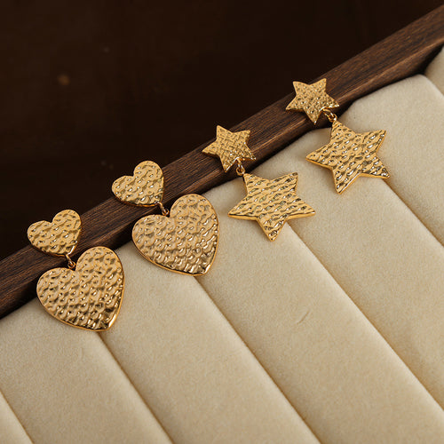 Gold hammered heart and star double drop earrings on cream tray