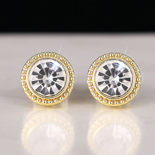 Pair of gold beaded bezel clear stone studs on white reflective background