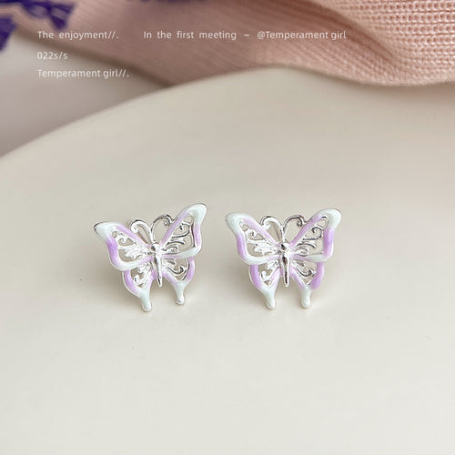 Lilac enamel silver butterfly studs on cream surface