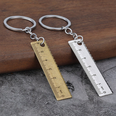 Antique brass-tone and silver-tone ruler keychains displayed side by side.