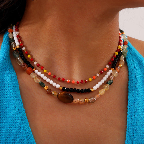 Model wearing layered black white colorful and natural stone beaded necklaces