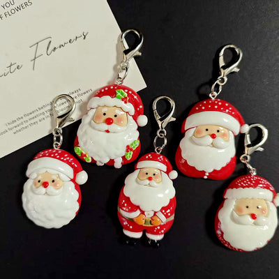 Five red white Santa resin lobster clasp keychains on dark surface
