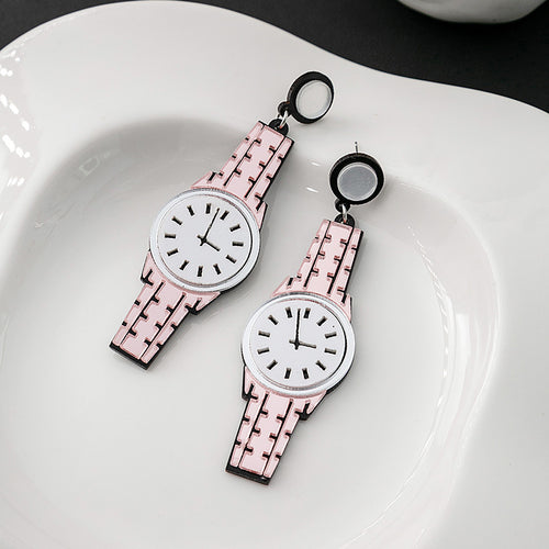Light pink acrylic watch earrings on white scalloped plate