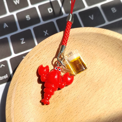 Red resin lobster and beer mug charm on red phone strap on wooden dish