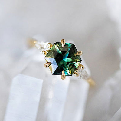 Gold hexagon green center ring with clear pear sides on white crystal