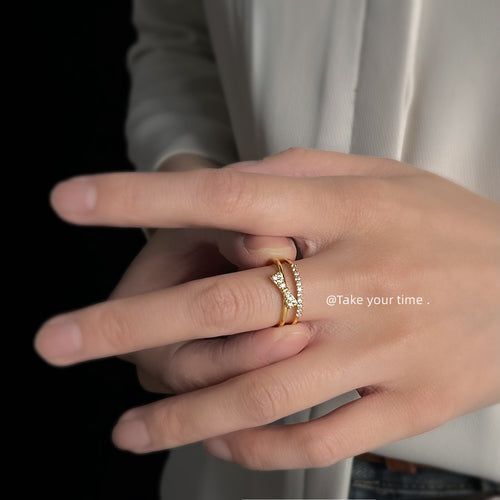 Model hand wearing gold double-band bow crystal ring