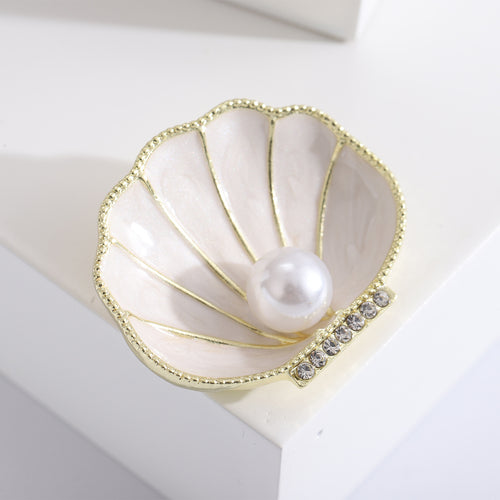 Close front view showing a ridged enamel shell with gold- or silver-tone edging and a central pearl-like bead
