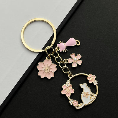 Front product photo of pink cat sakura and faux pearl enamel charm keychain showing the pictured design arrangement