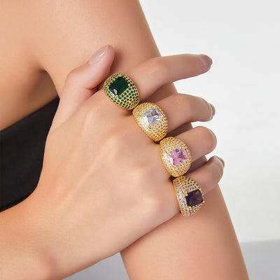 Four gold open pave rings with green clear pink purple stones on hand