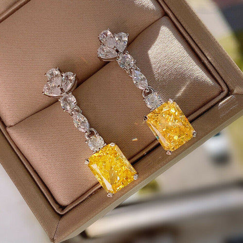 Yellow rectangular CZ long drop earrings angled on brown jewelry tray