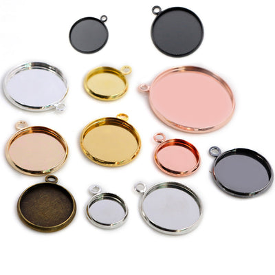 Front overview of round pendant tray blanks in mixed sizes and metal tones arranged on a light background