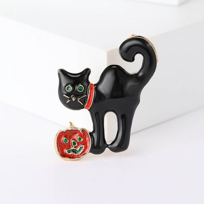 Black enamel cat brooch with red collar holding orange jack-o-lantern