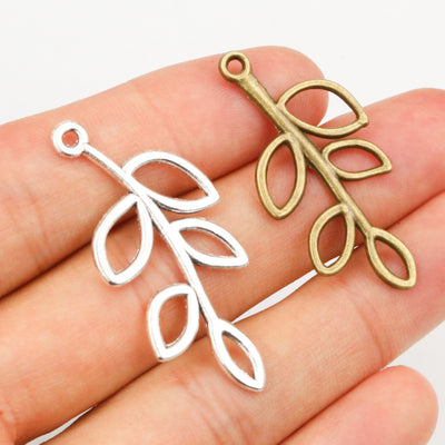 Hand held view of the open branch and leaf charms showing the front shape and finish