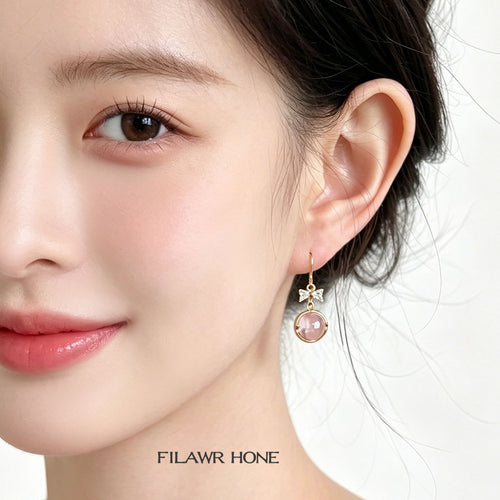 Gold pink glass bow drop earring worn on ear side profile