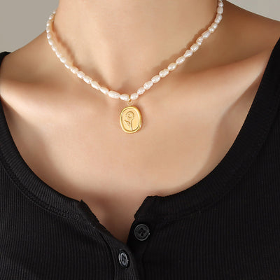 White pearl strand with gold sunflower oval pendant on black top