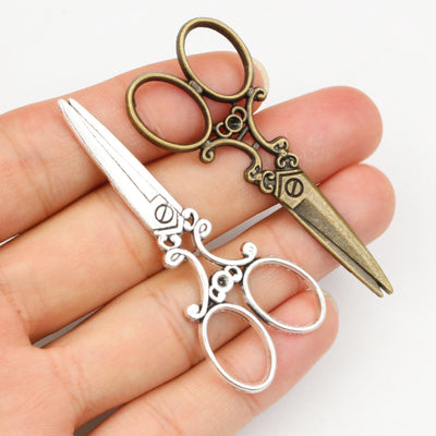 Assorted ornate scissors-shaped pendant charms in two finishes arranged together in the main product view