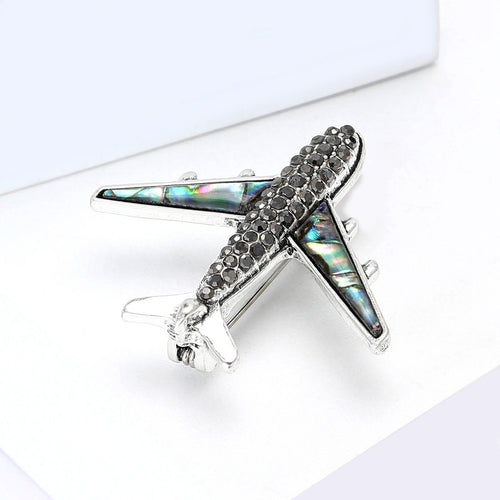 A silver tone airplane with crystal body and shell-inlay wings shown in a styled display.