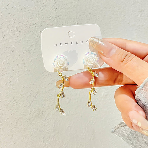 White rose gold vine crystal drop earrings on card held by hand