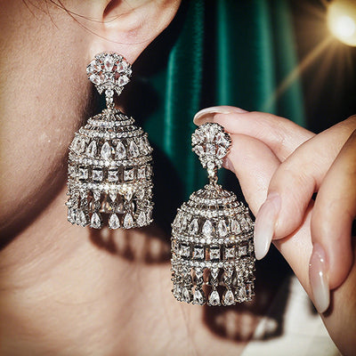 White gold pave chandelier bell earrings worn with one held by hand