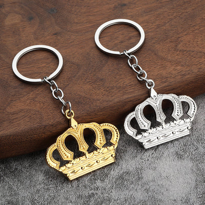 Gold-tone and silver-tone crown keychains displayed together on a wooden surface.