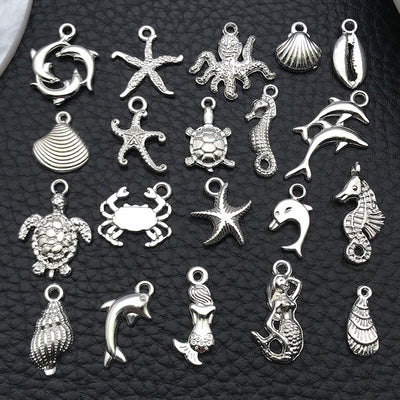 Black mermaid and dolphin charms arranged on a light background