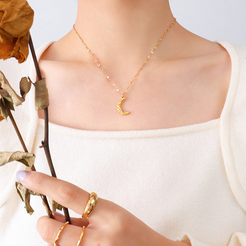 Gold textured crescent moon pendant necklace worn on cream top