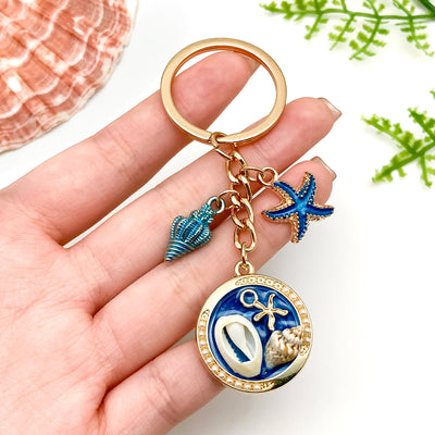 Image 1 showing a person holding a keychain with an animal and fish.