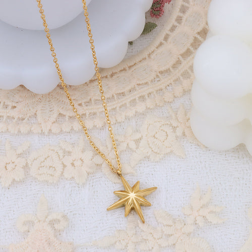 Gold starburst pendant angled on cream lace backdrop