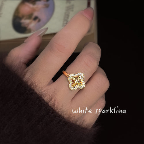 Gold open clover knot pavé ring worn on finger close-up