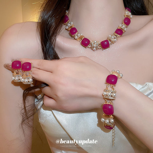 Model wearing gold magenta resin pearl necklace earrings and bracelet