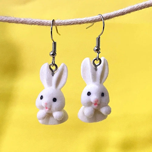 Front-facing white flocked rabbit drop earrings with pink noses on yellow background