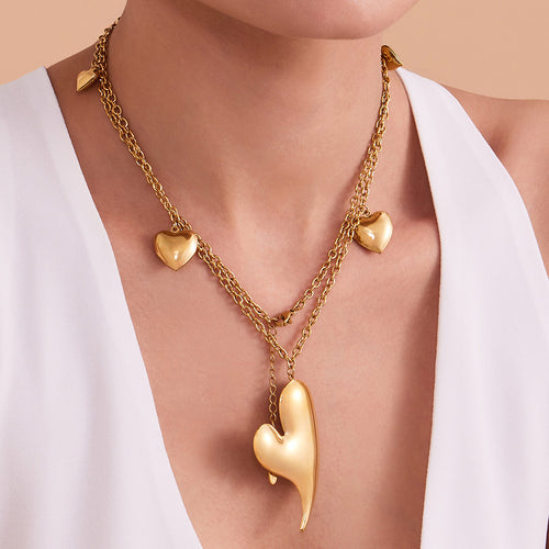 Neckline view of long asymmetrical heart station necklaces in main image 1.