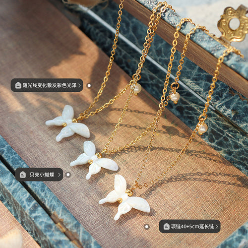 Three shell butterfly necklaces flat on fabric with length and shell labels