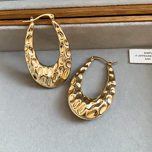 Chunky open oval hoops with an irregular hammered surface shown in a styled view.