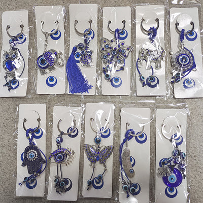 Twelve packaged blue evil eye metal keychains laid out in two rows