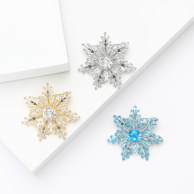 Gold silver and blue CZ snowflake brooches on white blocks
