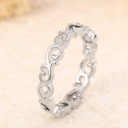 Silver hollow vine scroll ring angled on beige textured surface