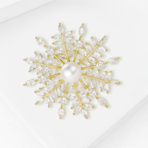 Gold CZ snowflake brooch angled on white surface
