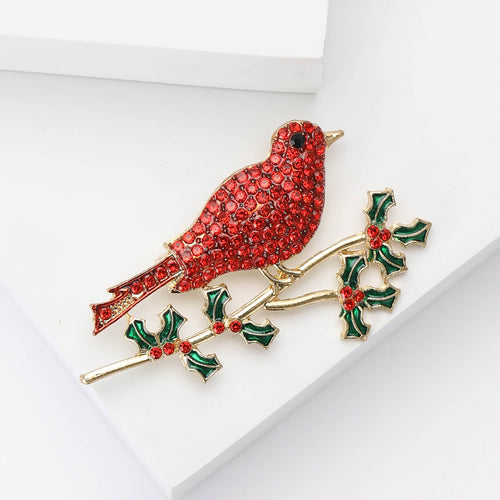 Red crystal bird brooch angled on white display blocks