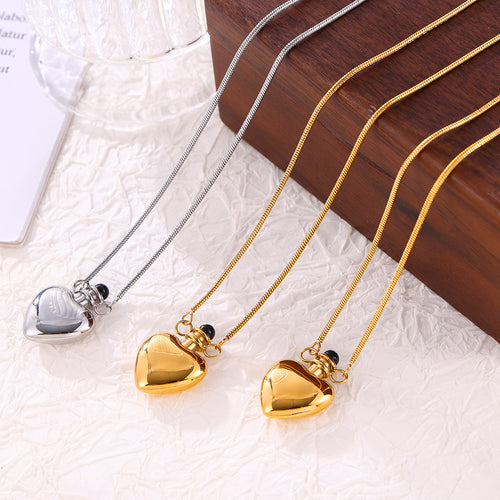 Steel and gold heart bottle pendants on textured surface