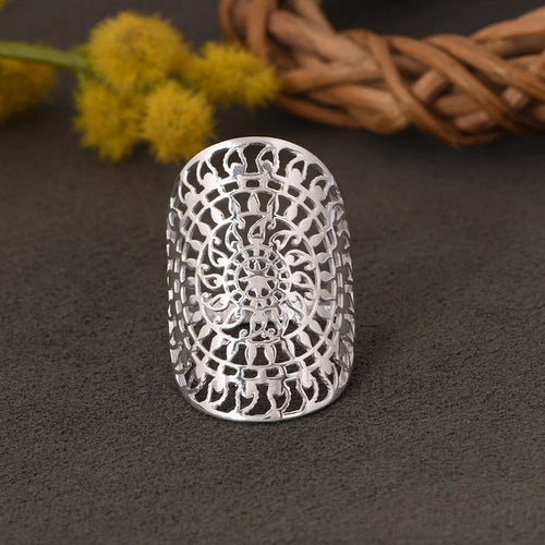 Silver filigree elongated ring upright on dark fabric with dried flowers
