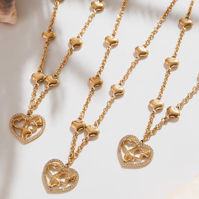 Three gold heart station necklaces with open zircon heart pendants flat lay