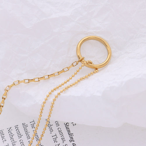 Close-up of gold circle connector joining box and ball chains