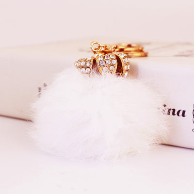 Close-up of a clear stone crown cap above a white fluffy pom pom.