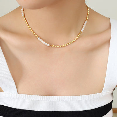 Model wearing gold disc and pearl segmented necklace with striped tank top