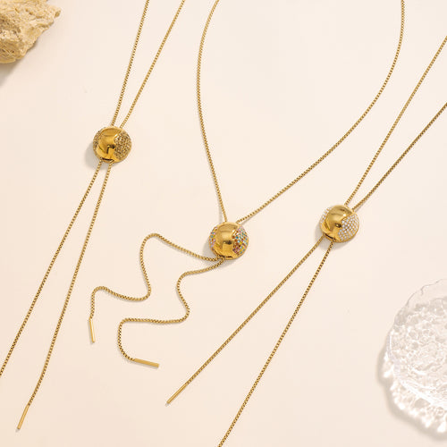 Three gold hemisphere zircon pull-through necklaces on beige surface