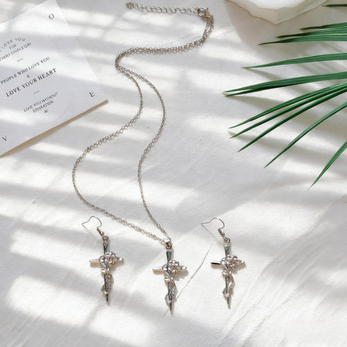 Silver rose cross necklace and matching fishhook earrings on white cloth