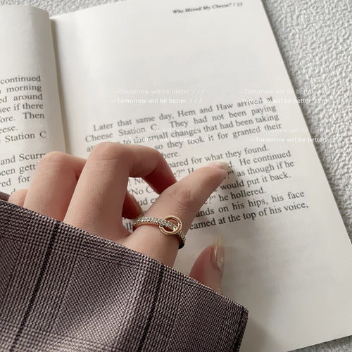Model hand wearing gold circle crystal ring on book