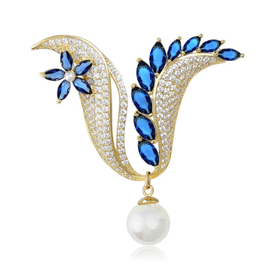 Front view of blue crystal floral plume brooch with a hanging pearl-like bead against a white background.
